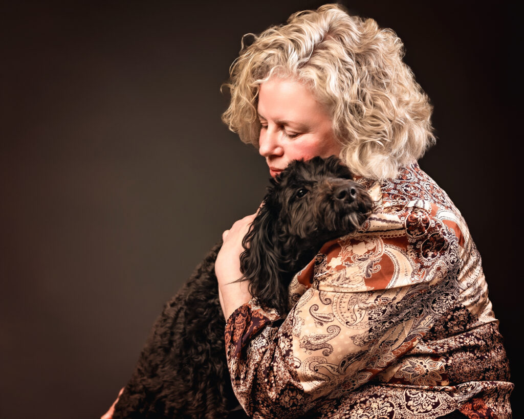 Woman hugs dog in pet portrait studio session