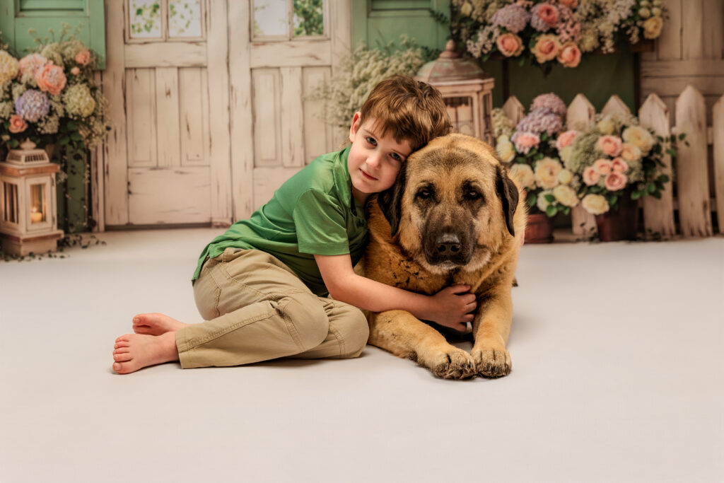Young boy and dog pose on spring backdrop in portrait studio 