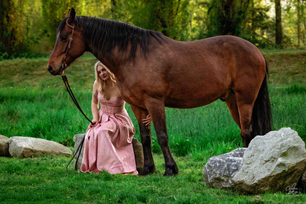 woman sitting next to her horse holding its leg